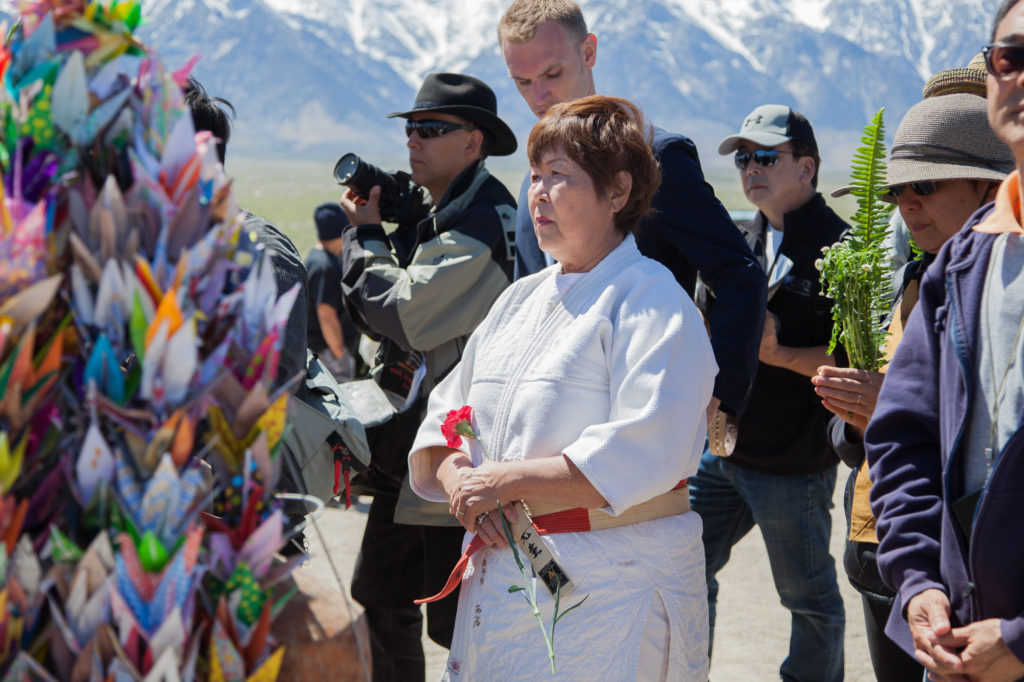An attendee holds a flower during the interfaith service to place on the I Rei To tower to honor those who were interned at Manzanar. Photo by Joanne Kim