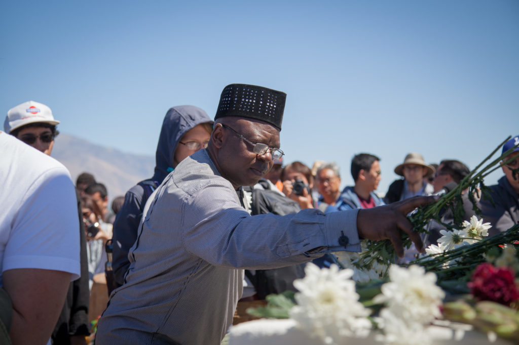 Attendee places a flower on the I Reo To/Soul Consoling Tower monument to honor those were forced to live in the Manzanar camp. Photo by Joanne Kim