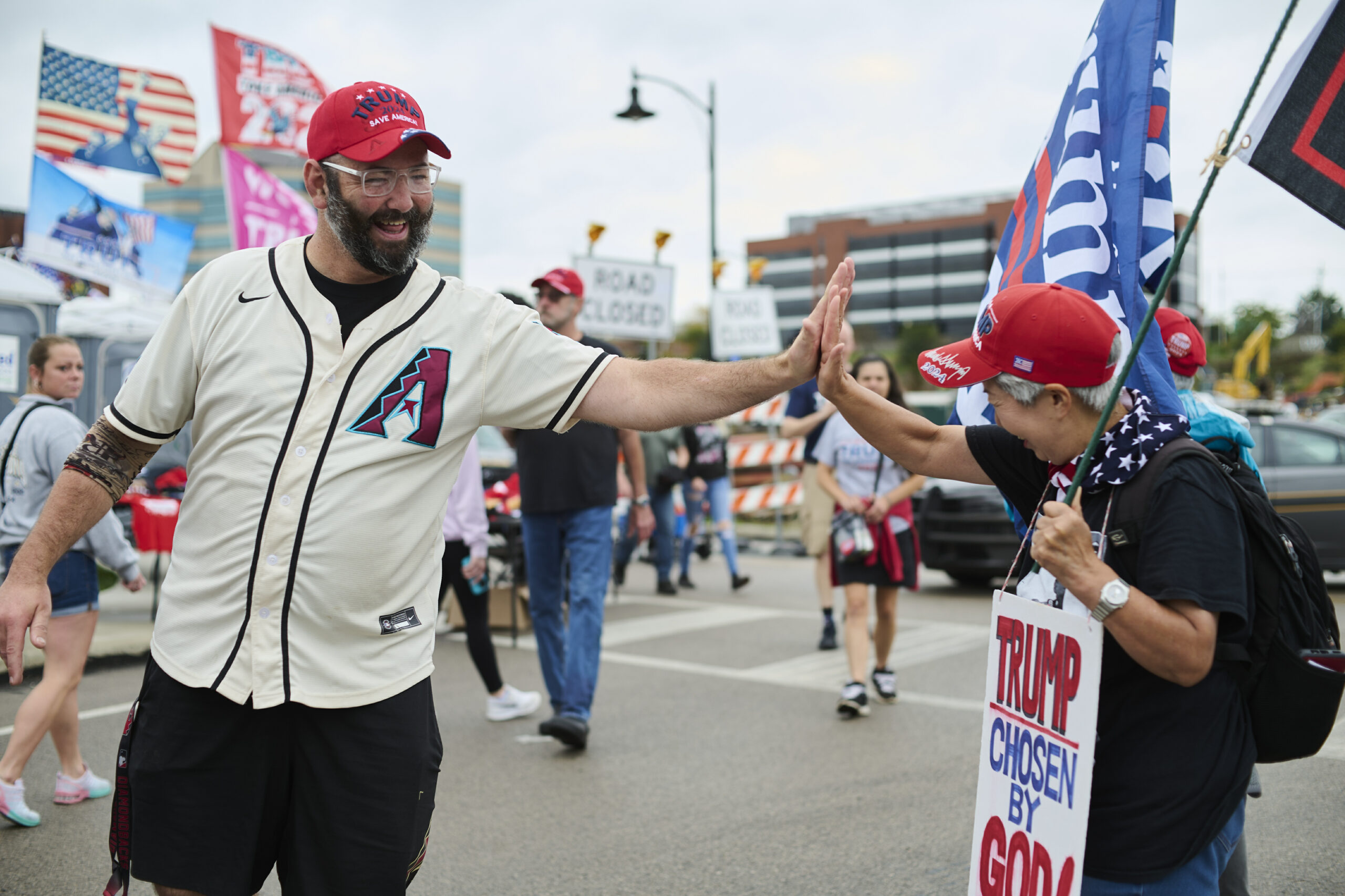 Two Trump supporters high-five one another before a rally for the former president on Sept. 29 in Erie.