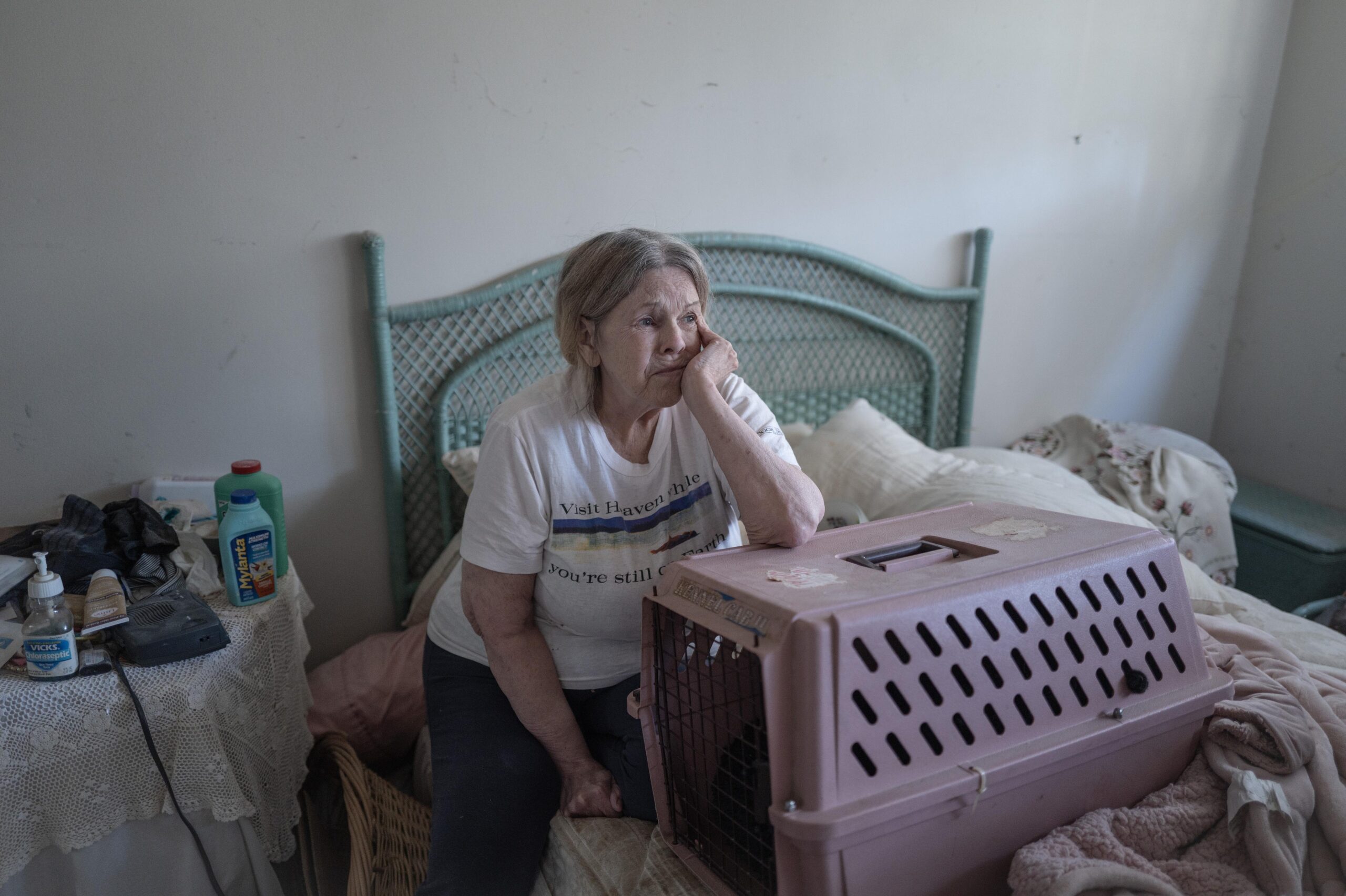 Joanne sits on her bed and soothes her cat as she watches movers clear out belongings from her home. Erickson feared more than anything the prospect of living in her 20-year-old VW Beetle with her cat.