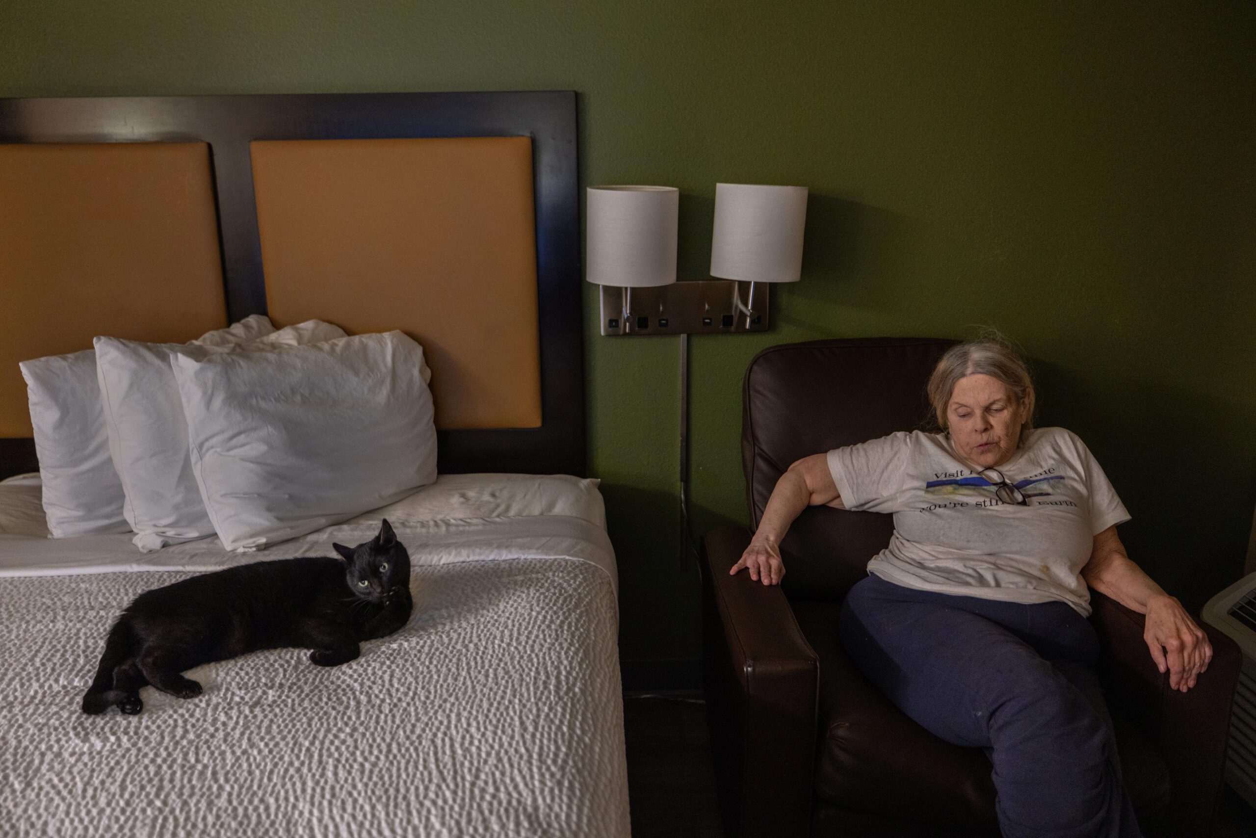 Exhausted after a long day of moving, Erickson and her cat, Muriel, relax in their hotel room. “We’re scared. I’m scared,” said Erickson, who survived on a monthly $1,799 Social Security check.